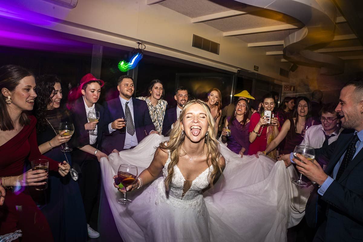 Una novia está bailando frente a una multitud de personas en una recepción de boda.