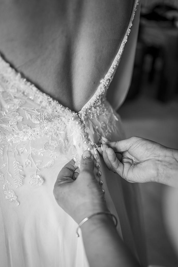 Una mujer está ayudando a una novia con su vestido de novia en una foto en blanco y negro.