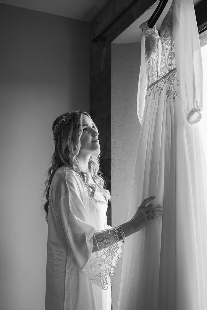 Una fotografía en blanco y negro de una novia mirando su vestido de novia.