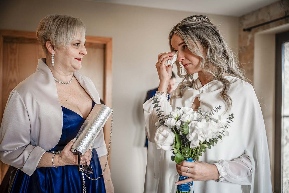 Una novia está llorando mientras está de pie junto a su madre.