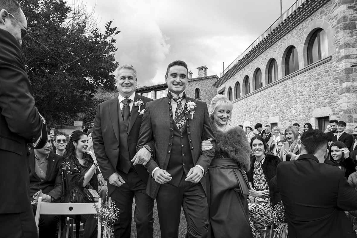 Una fotografía en blanco y negro de una novia y un novio caminando por el pasillo en una boda.
