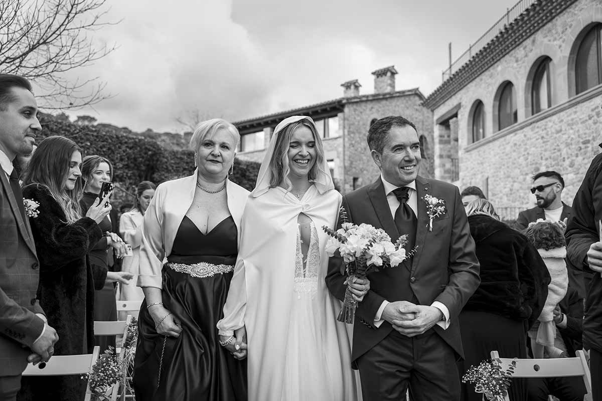 Una fotografía en blanco y negro de una novia y un novio caminando por el pasillo en su boda.