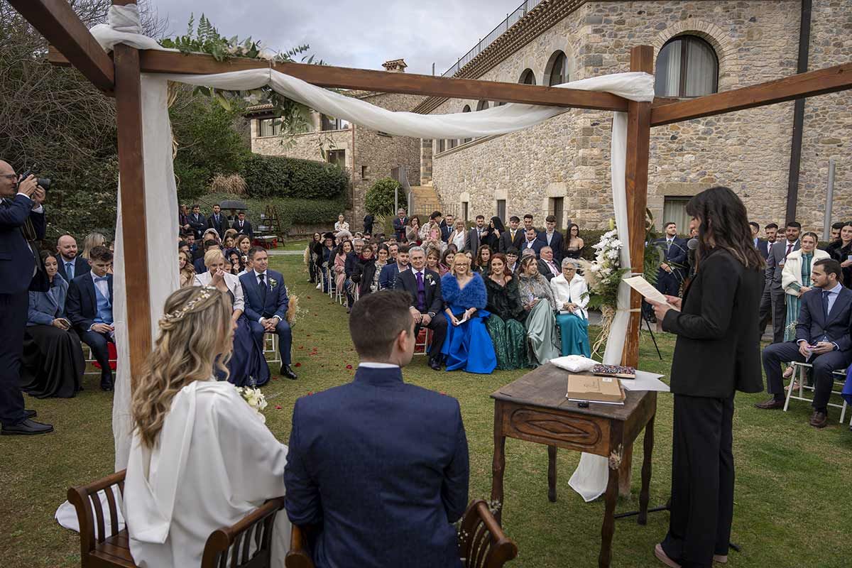 Una novia y un novio están sentados bajo un dosel durante su ceremonia de boda.