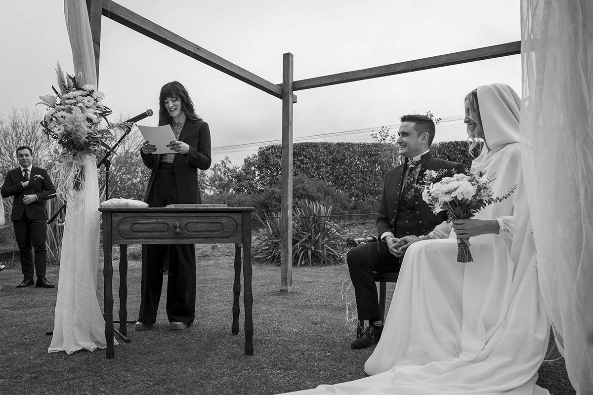Una novia y un novio están sentados bajo un dosel en una ceremonia de boda.