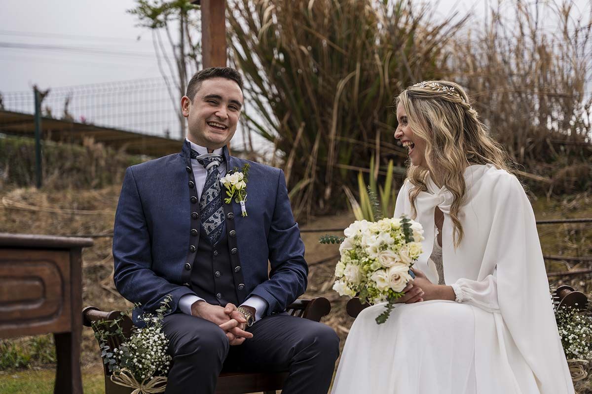 Una novia y un novio están sentados uno al lado del otro en un banco.