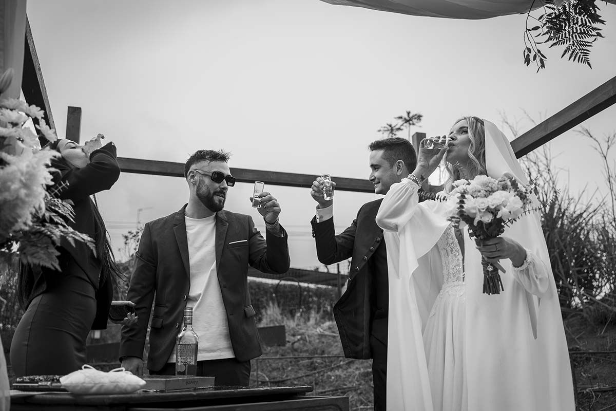 Una fotografía en blanco y negro de unos novios brindando en su boda.