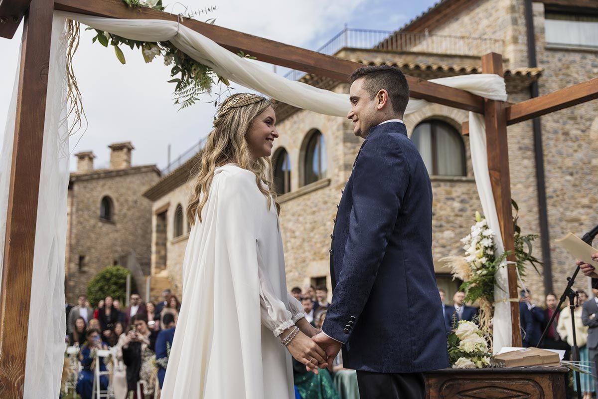 Una novia y un novio se toman de la mano durante su ceremonia de boda.