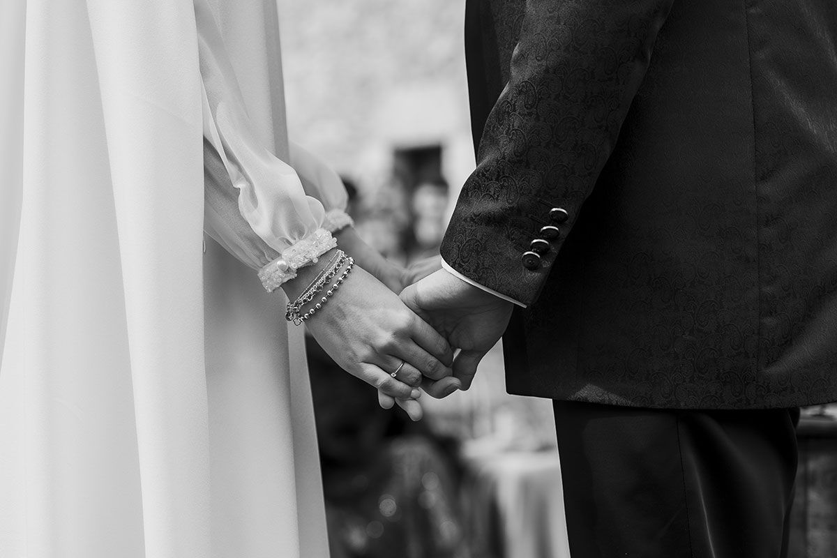 Una novia y un novio se toman de la mano durante su ceremonia de boda.