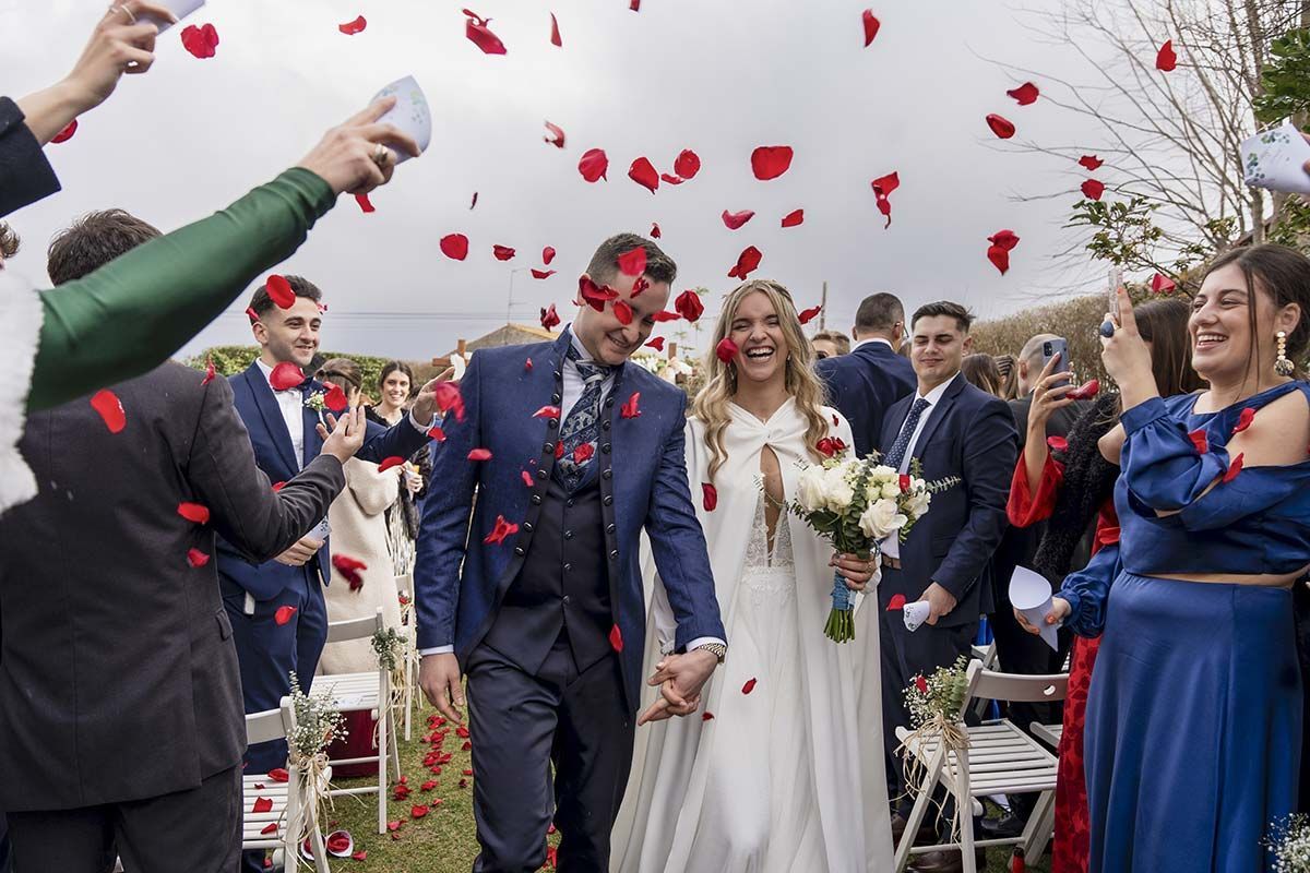 Una novia y un novio caminan por el pasillo rodeados de confeti.