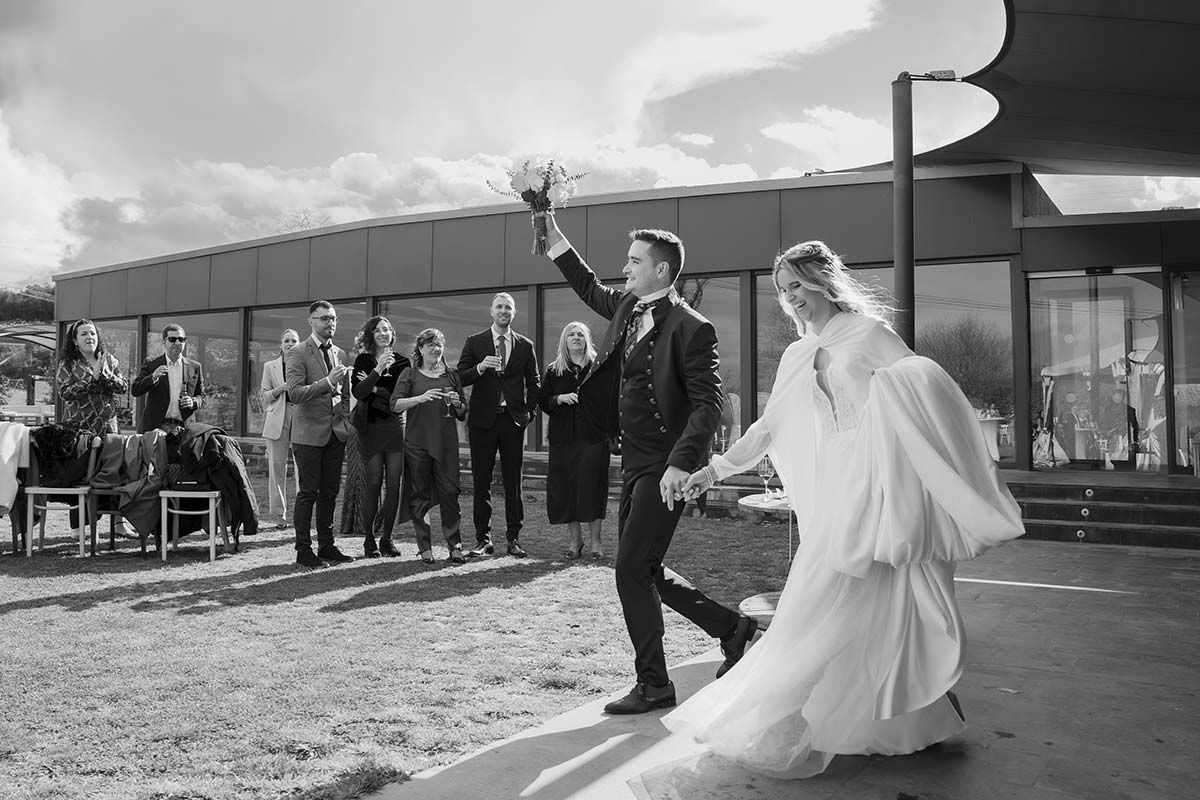 Una fotografía en blanco y negro de una novia y un novio caminando por el pasillo en su boda.