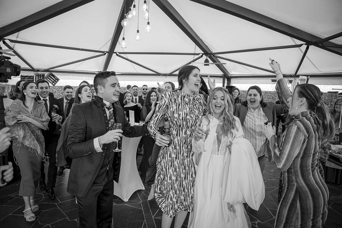 Un grupo de personas está bailando en una carpa en una recepción de boda.