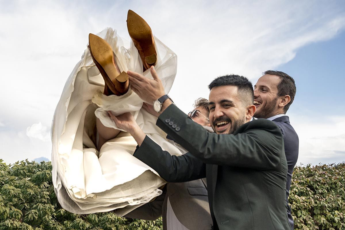 Un hombre con traje sostiene a una novia en sus brazos.