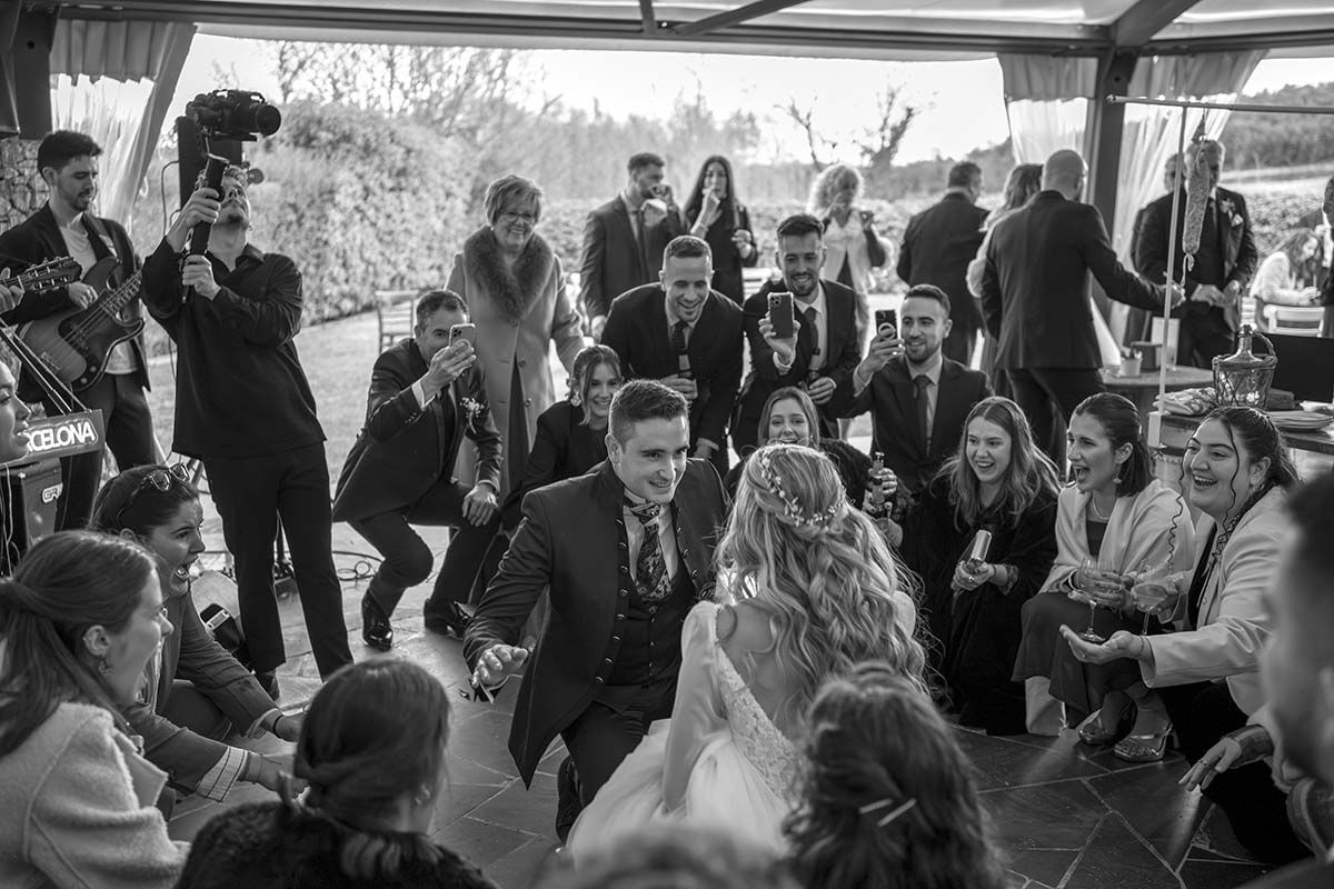 Una fotografía en blanco y negro de unos novios bailando con sus invitados a la boda.