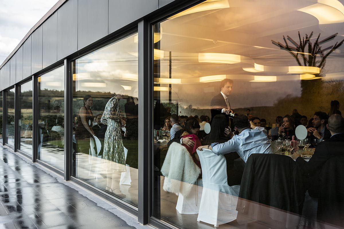 Un grupo de personas están sentadas en mesas frente a una gran ventana.