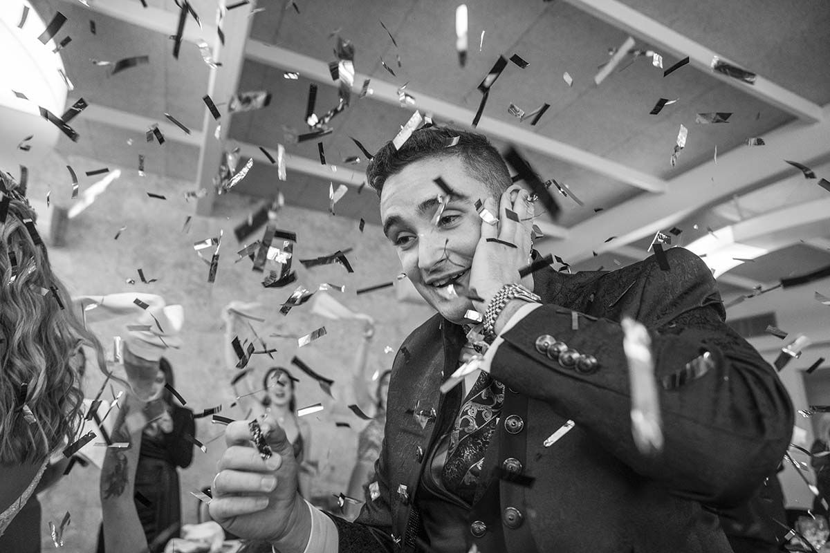 Un hombre con traje está siendo bañado con confeti en una fiesta.