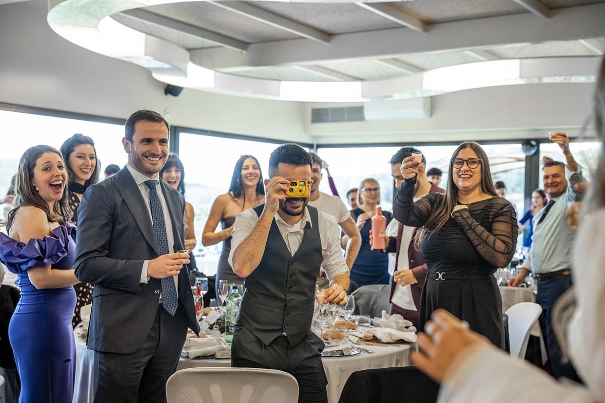 Un hombre está tomando una fotografía de un grupo de personas en una recepción de boda.