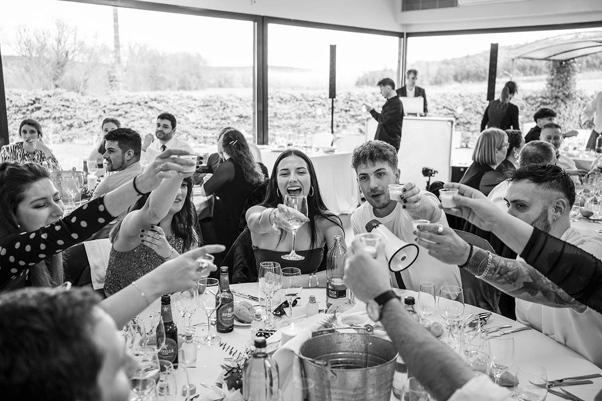 Un grupo de personas están sentadas en una mesa brindando con copas de champán.