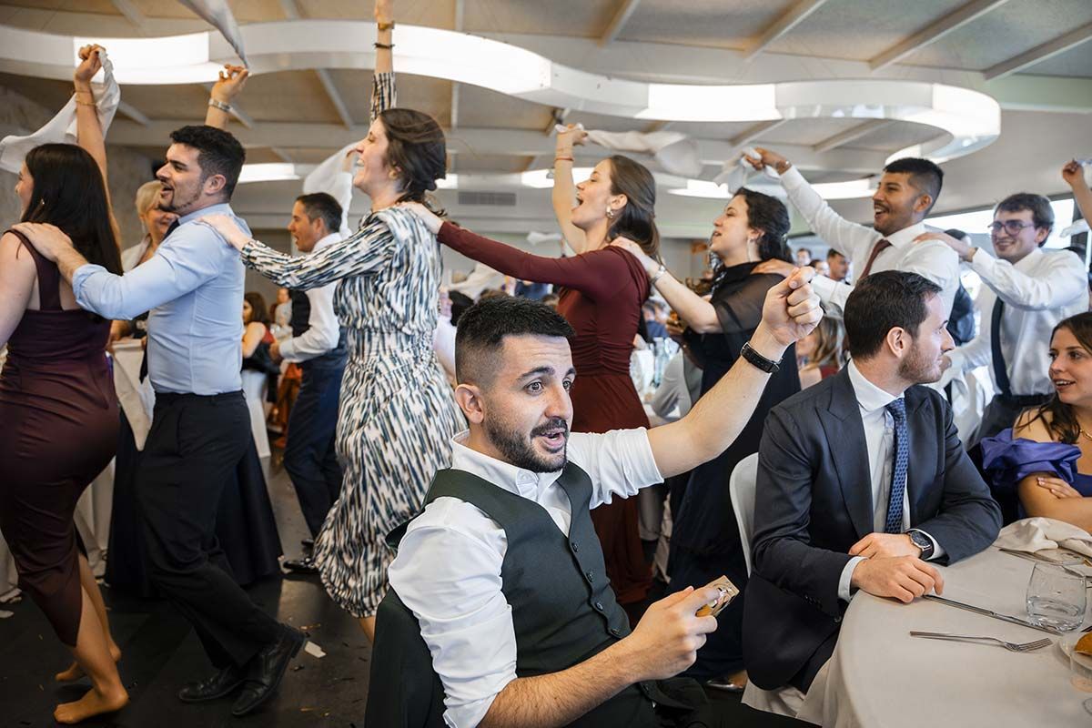 Un grupo de personas está bailando en una sala en una recepción de boda.