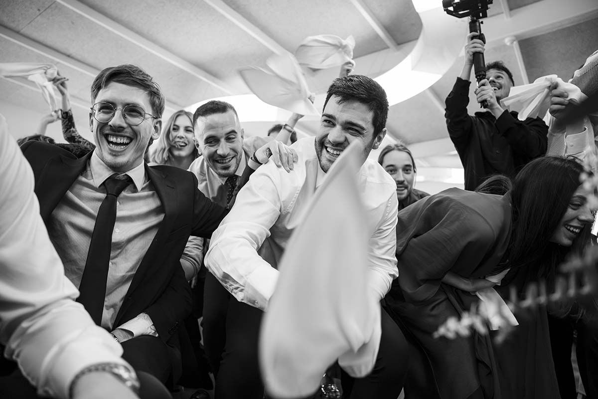 Una fotografía en blanco y negro de un grupo de personas bailando en una recepción de boda.