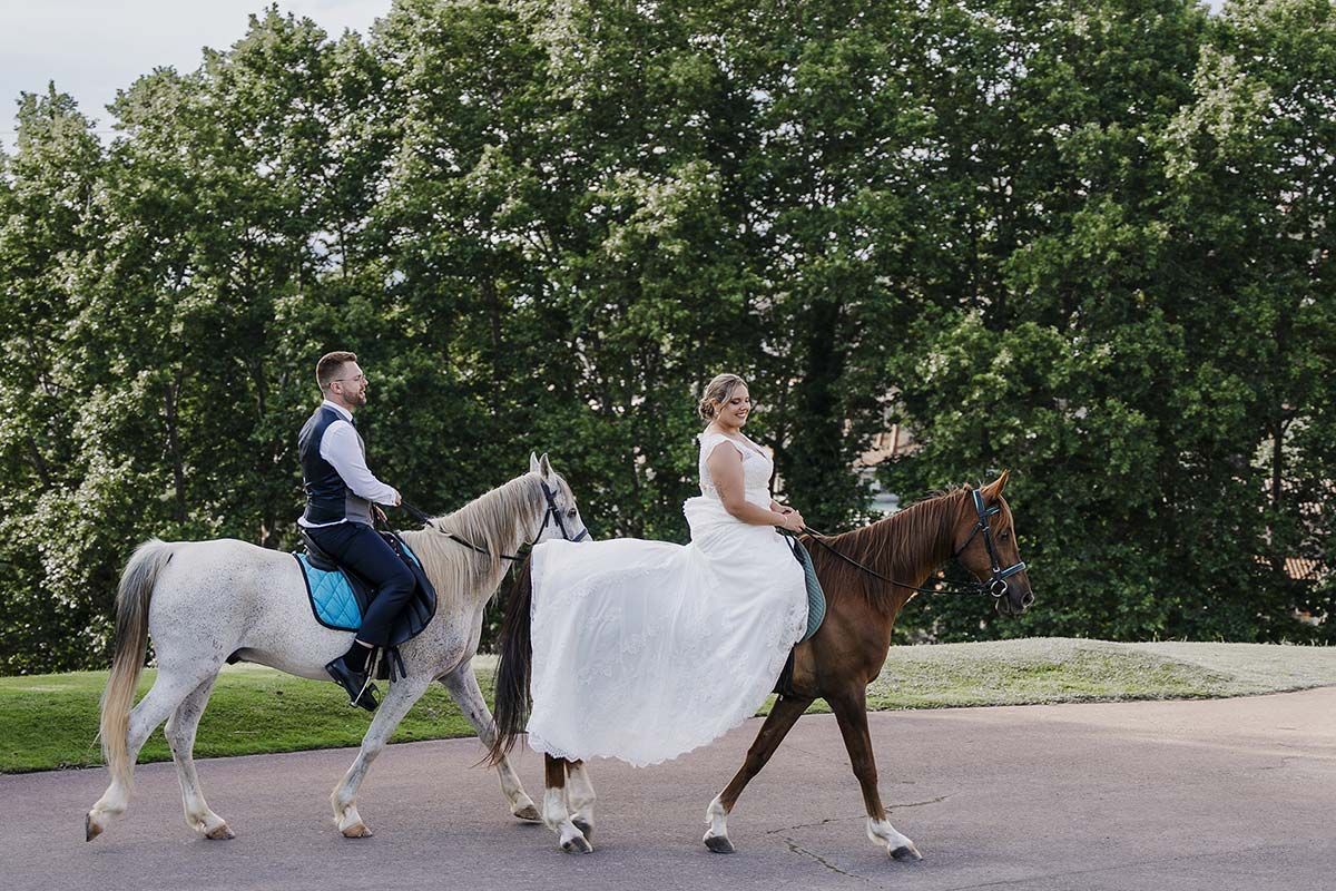 Una novia y un novio van a caballo por una carretera.