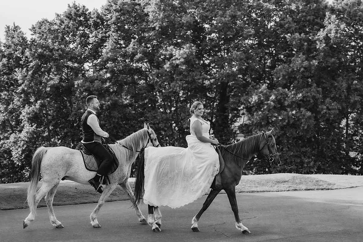 Una novia y un novio van a caballo por una carretera.