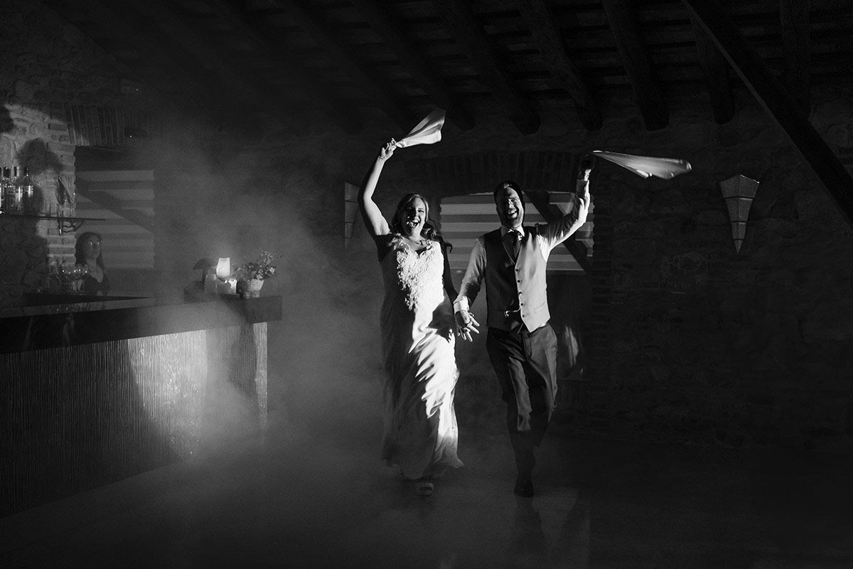 Una fotografía en blanco y negro de una novia y un novio bailando en una habitación oscura.
