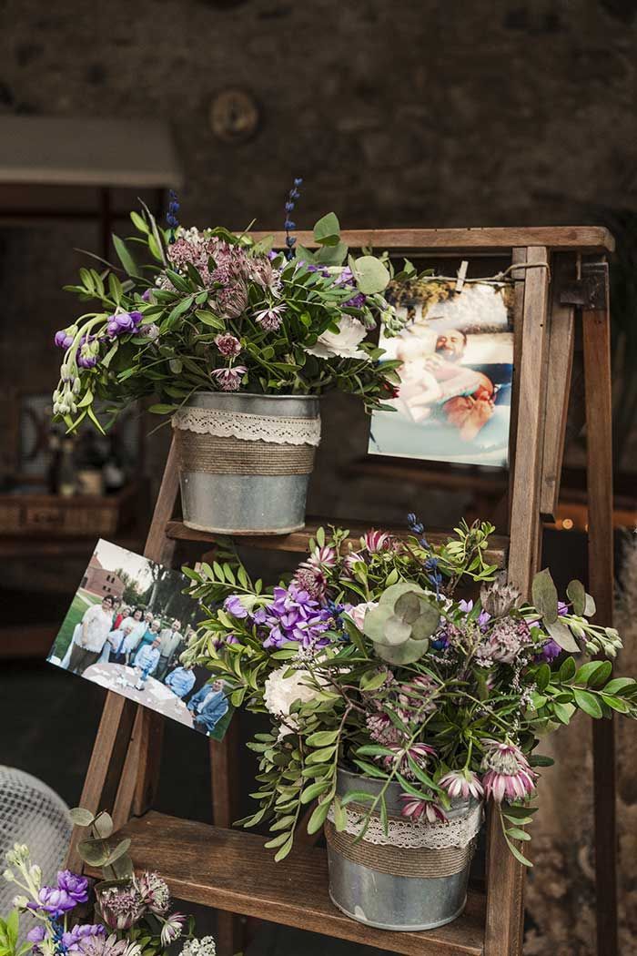Una escalera de madera llena de flores en macetas y cuadros.