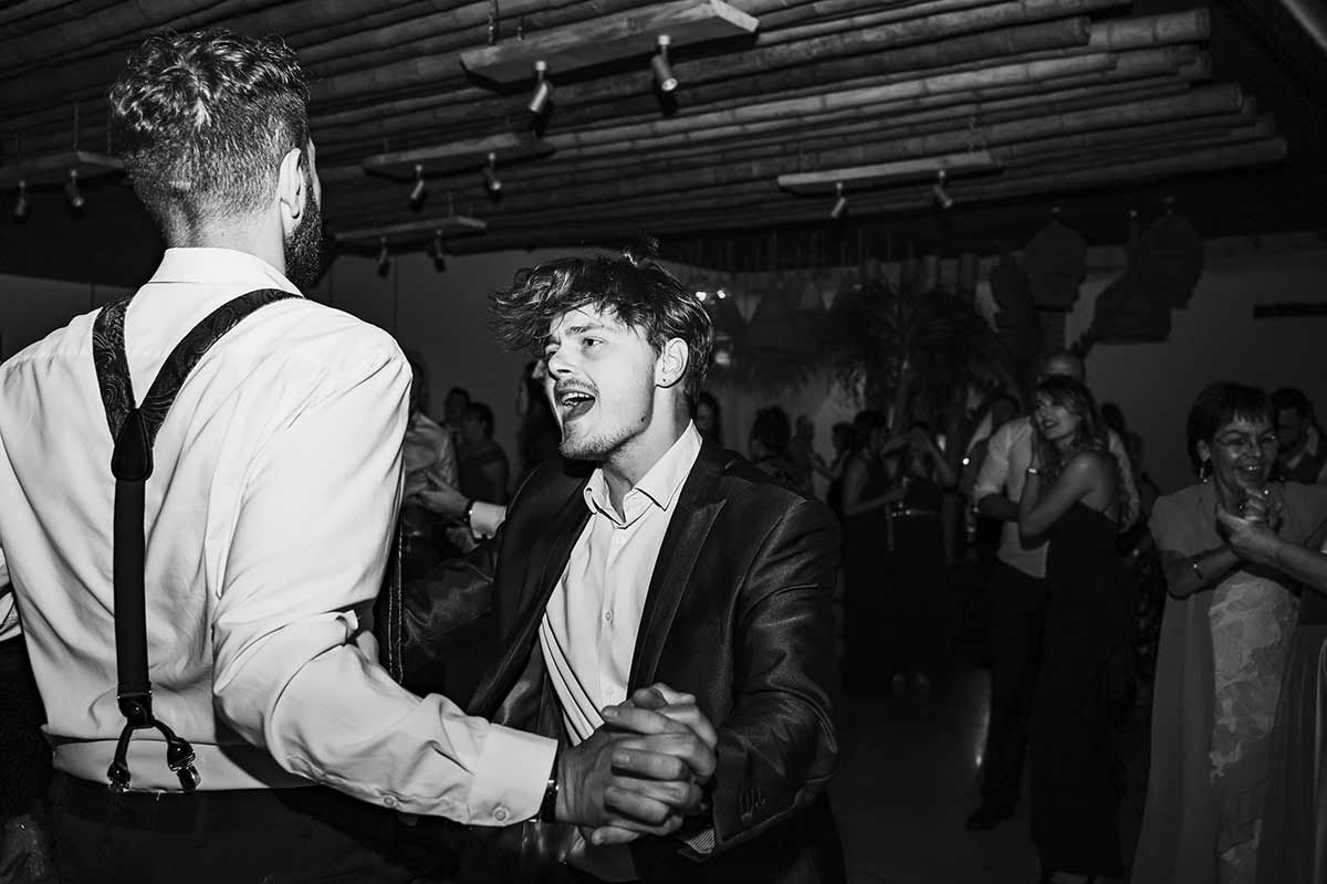 Una fotografía en blanco y negro de dos hombres bailando en una recepción de boda.