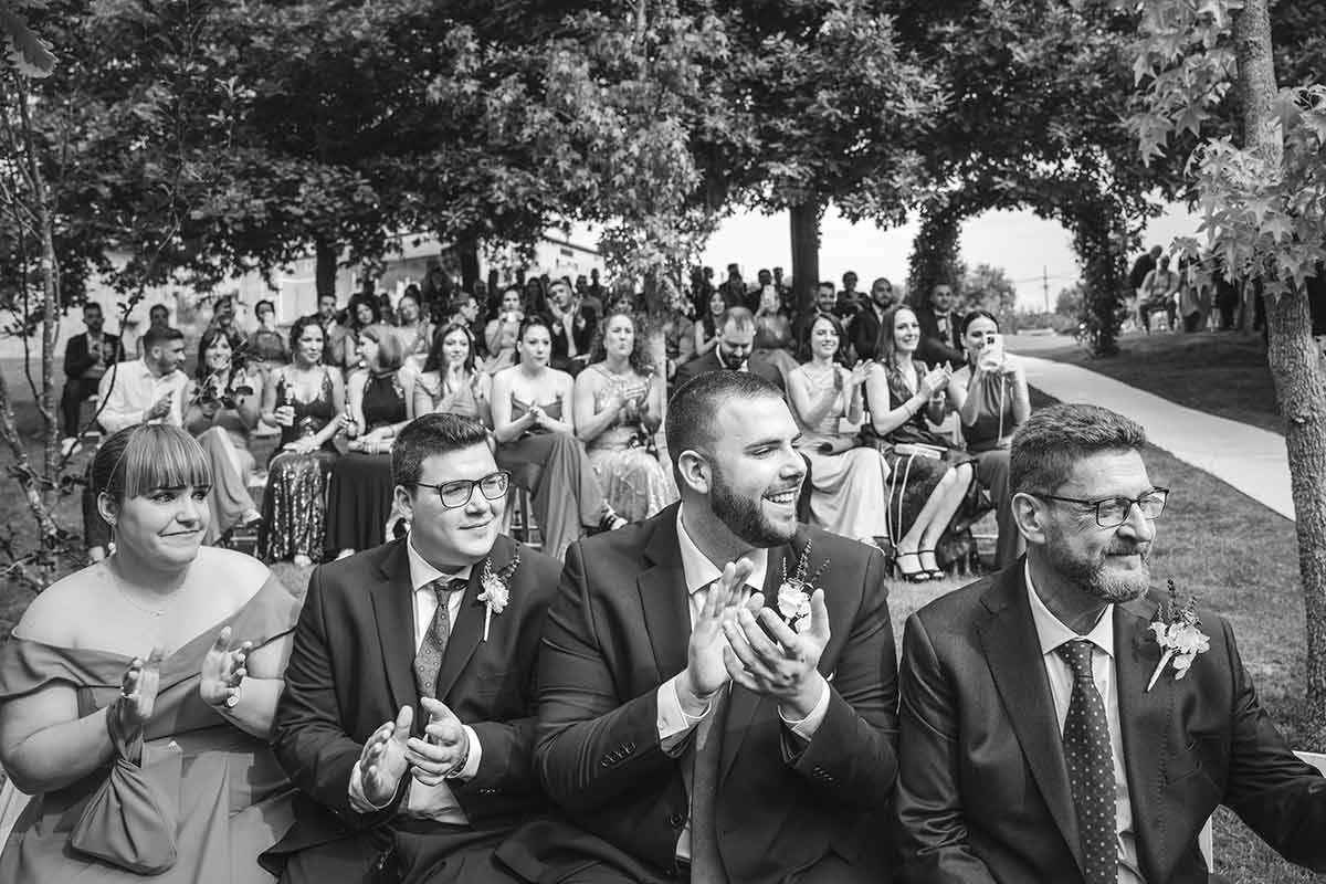 Una fotografía en blanco y negro de un grupo de personas aplaudiendo en una boda.
