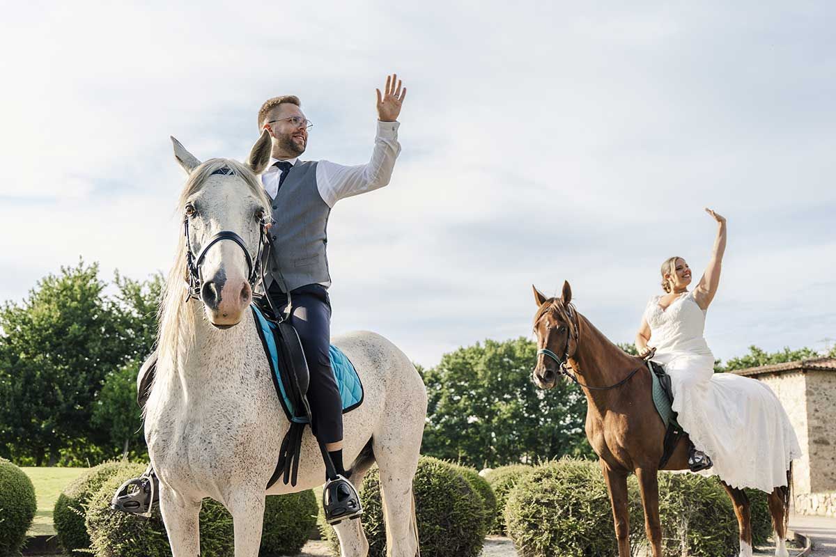 Una novia y un novio montan a caballo el día de su boda.