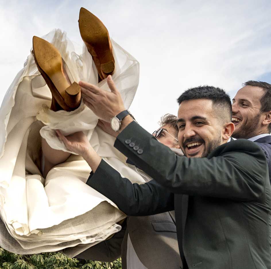 Un hombre con traje sostiene a una novia en sus brazos.