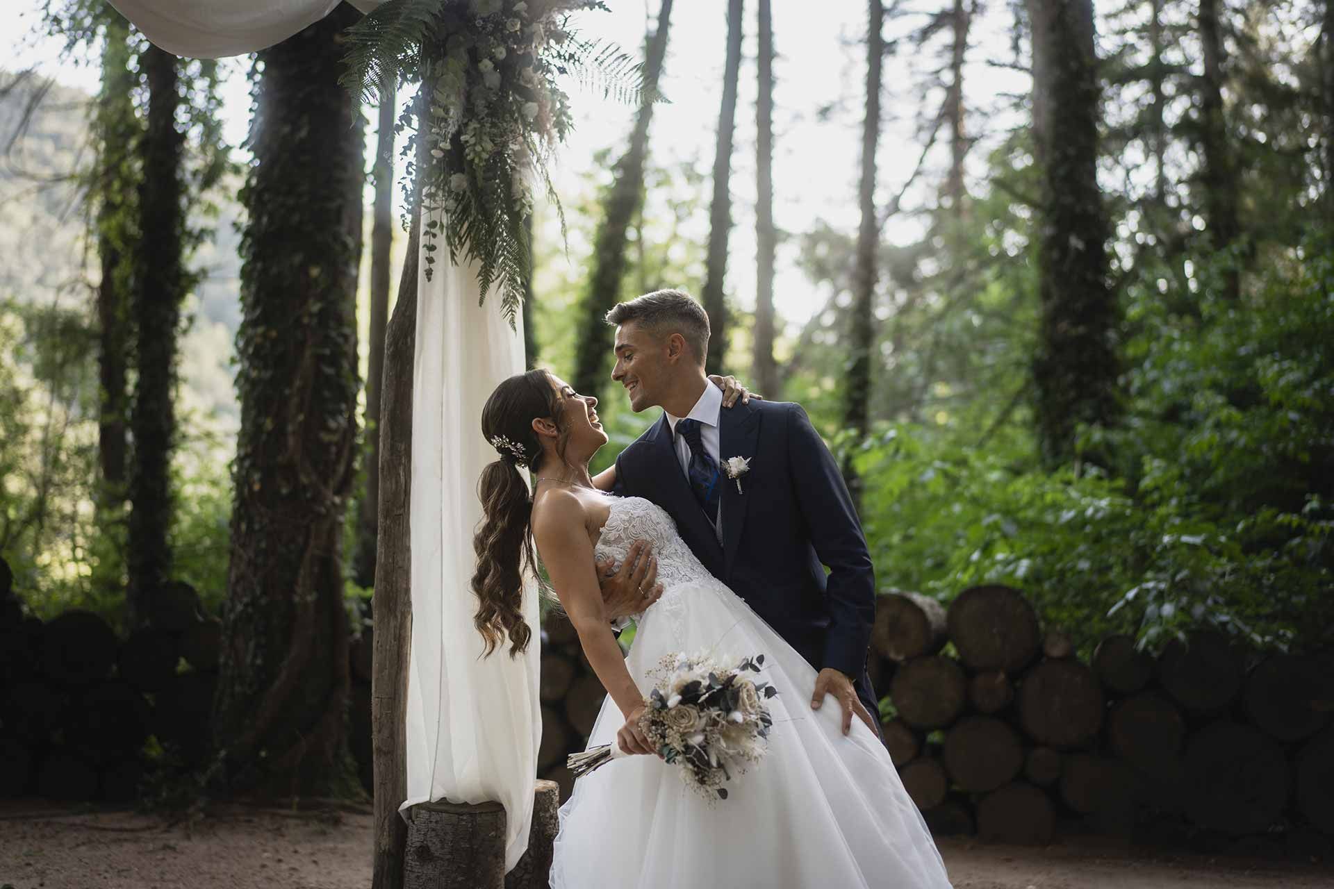 Una novia y un novio posan para una fotografía en el bosque.