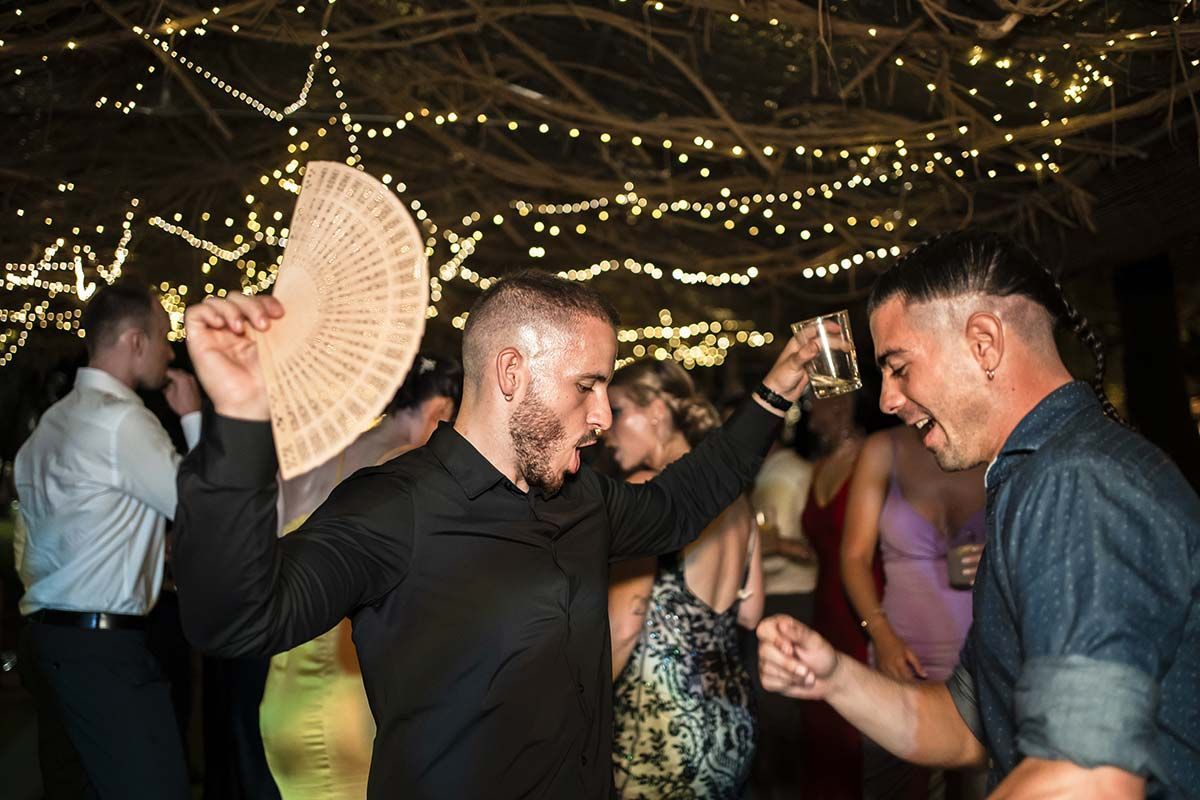 Un grupo de personas está bailando en una fiesta y un hombre sostiene un abanico en su mano.