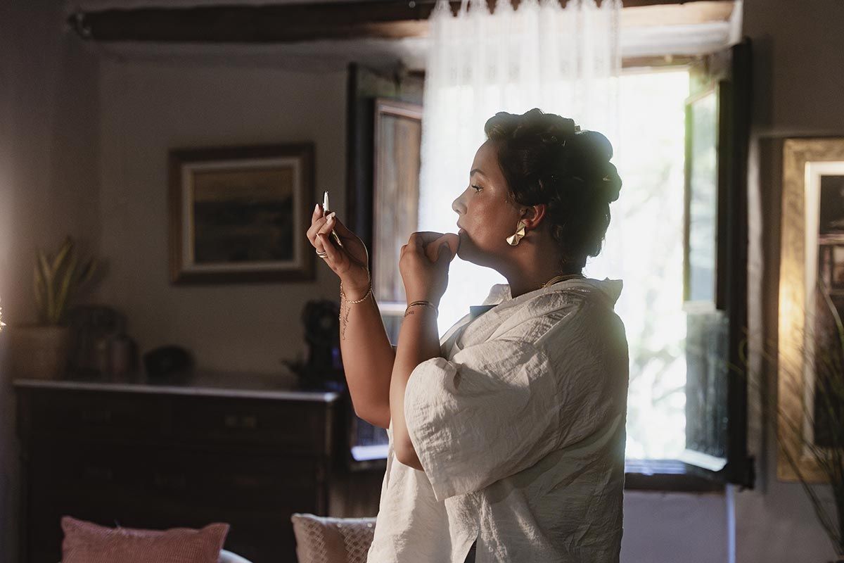 Una mujer se aplica lápiz labial frente a un espejo en una sala de estar.