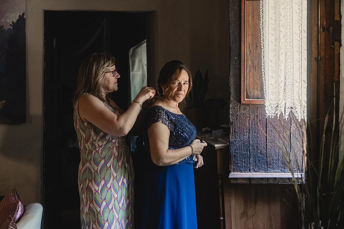 Una mujer está ayudando a otra mujer a prepararse para una boda.