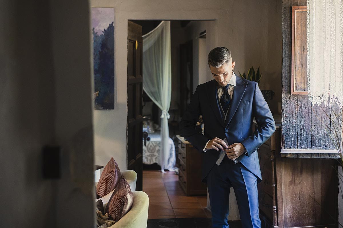 Un hombre con traje y corbata se prepara para su boda.