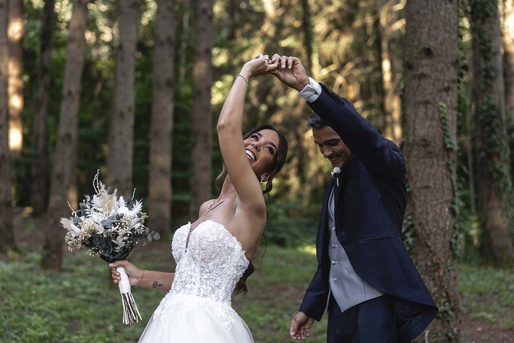 Una novia y un novio posan para una fotografía en el bosque.