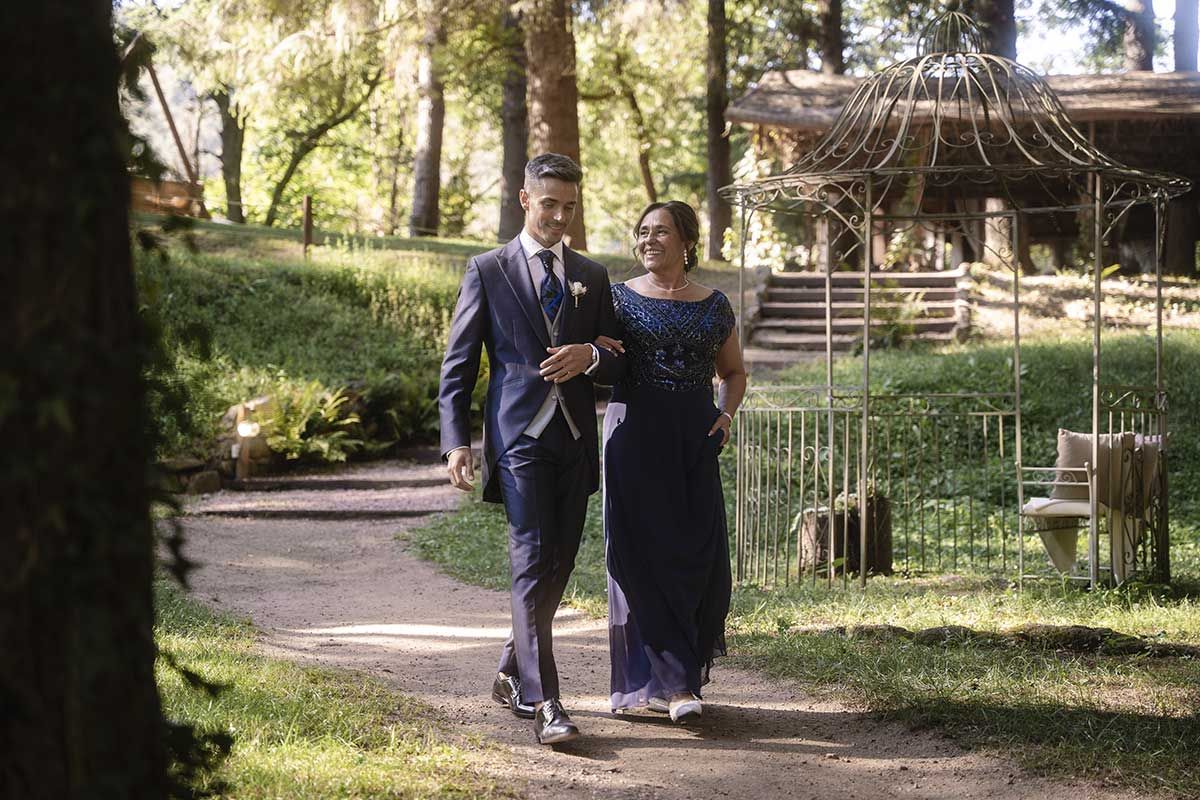 Una novia y un novio caminan por un sendero en el bosque.