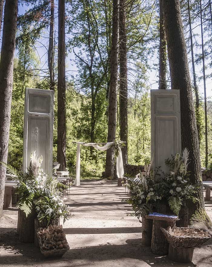 Una ceremonia de boda en el bosque con puertas blancas y flores.