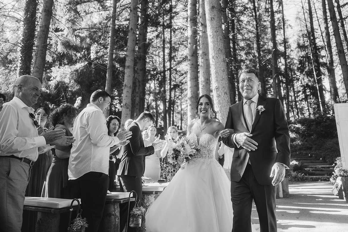 Una novia y un novio caminan hacia el altar en su boda en el bosque.