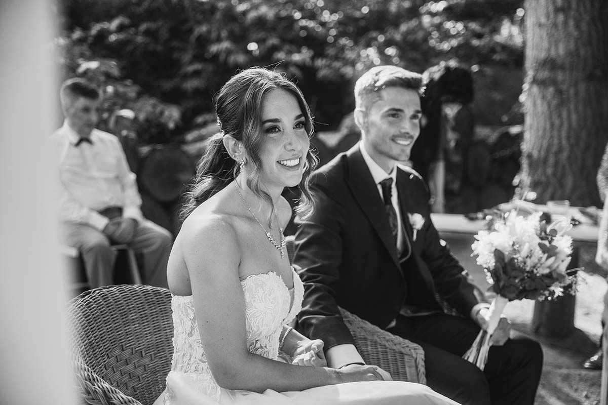 Una fotografía en blanco y negro de una novia y un novio sentados en un banco.