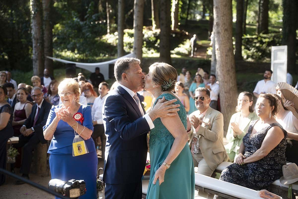 Un hombre y una mujer se besan delante de una multitud en una boda.