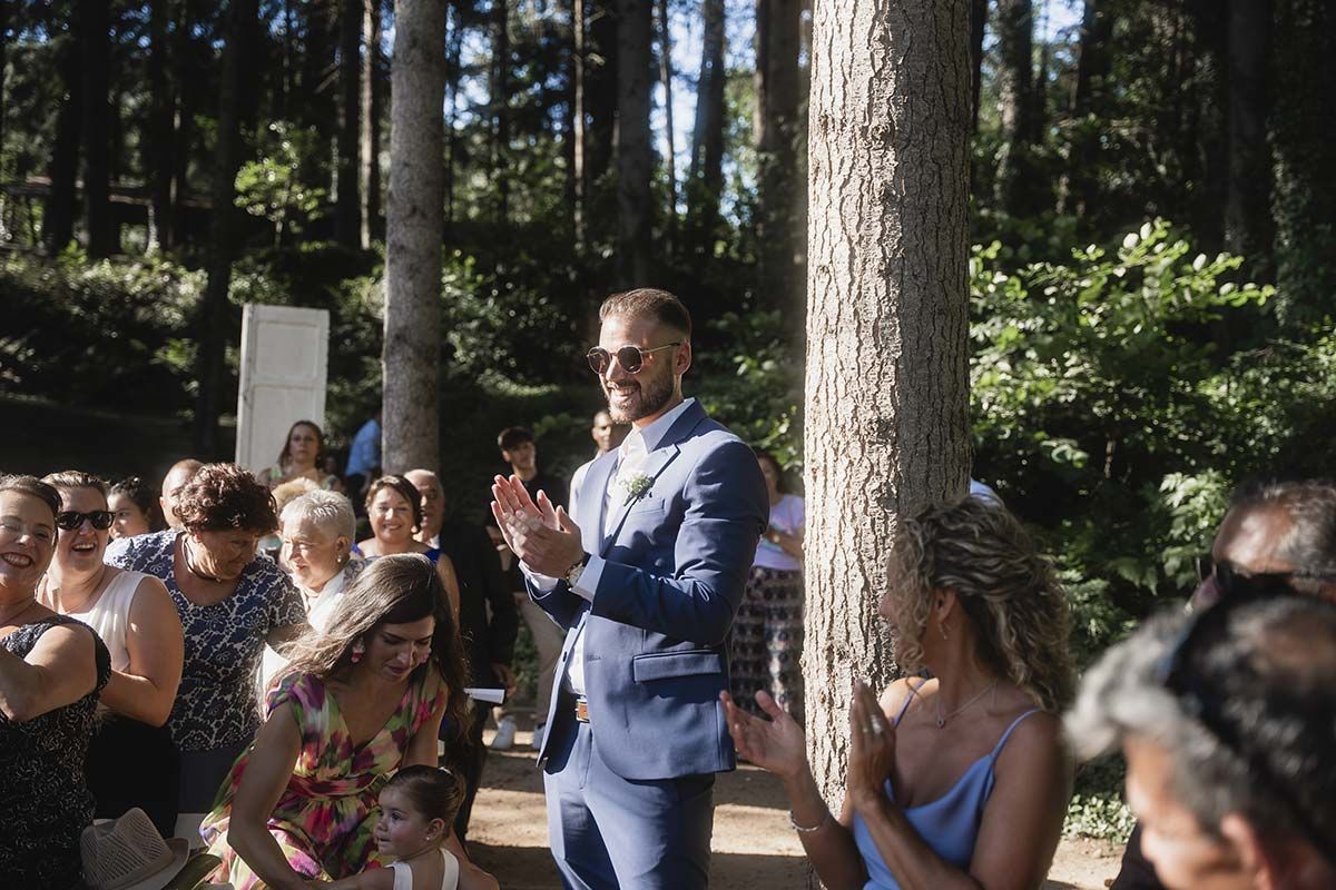 Un hombre con traje está parado frente a una multitud de personas en una boda.