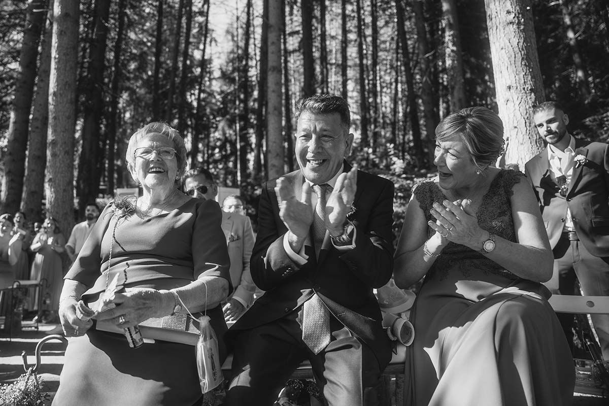 Un grupo de personas está sentada en el bosque aplaudiendo y riendo.