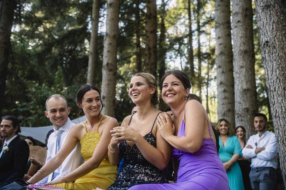 Un grupo de personas están sentadas en el bosque riendo.