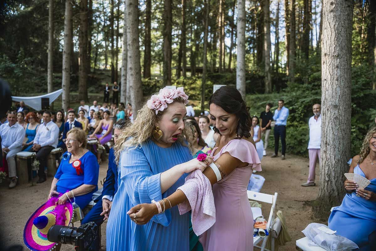 Dos mujeres están paradas una al lado de la otra en el bosque en una boda.