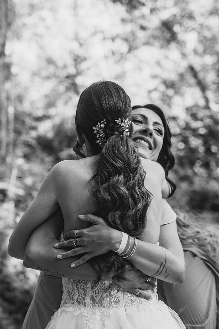 Una novia y su dama de honor se abrazan en una foto en blanco y negro.