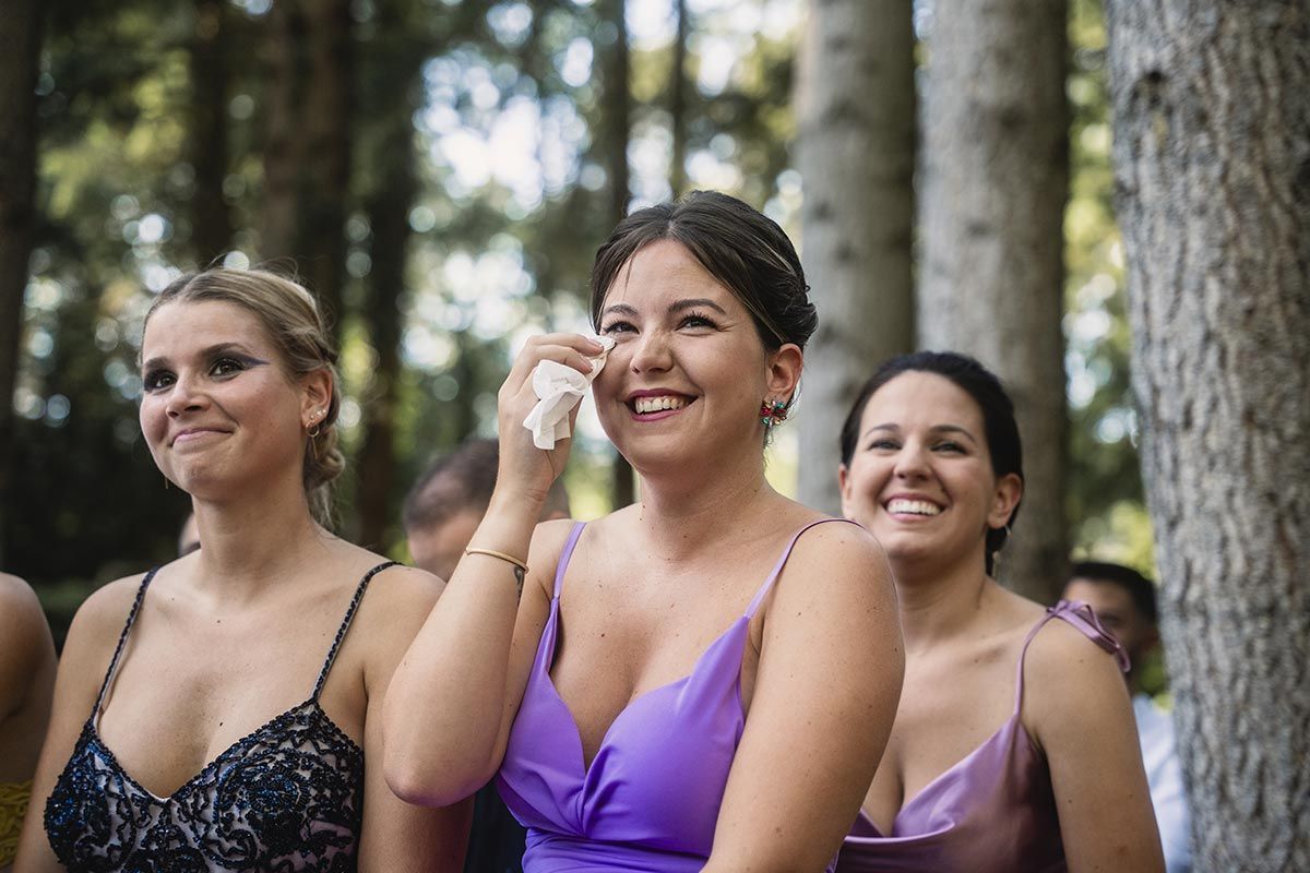 Una mujer con un vestido morado llora mientras observa una ceremonia de boda.