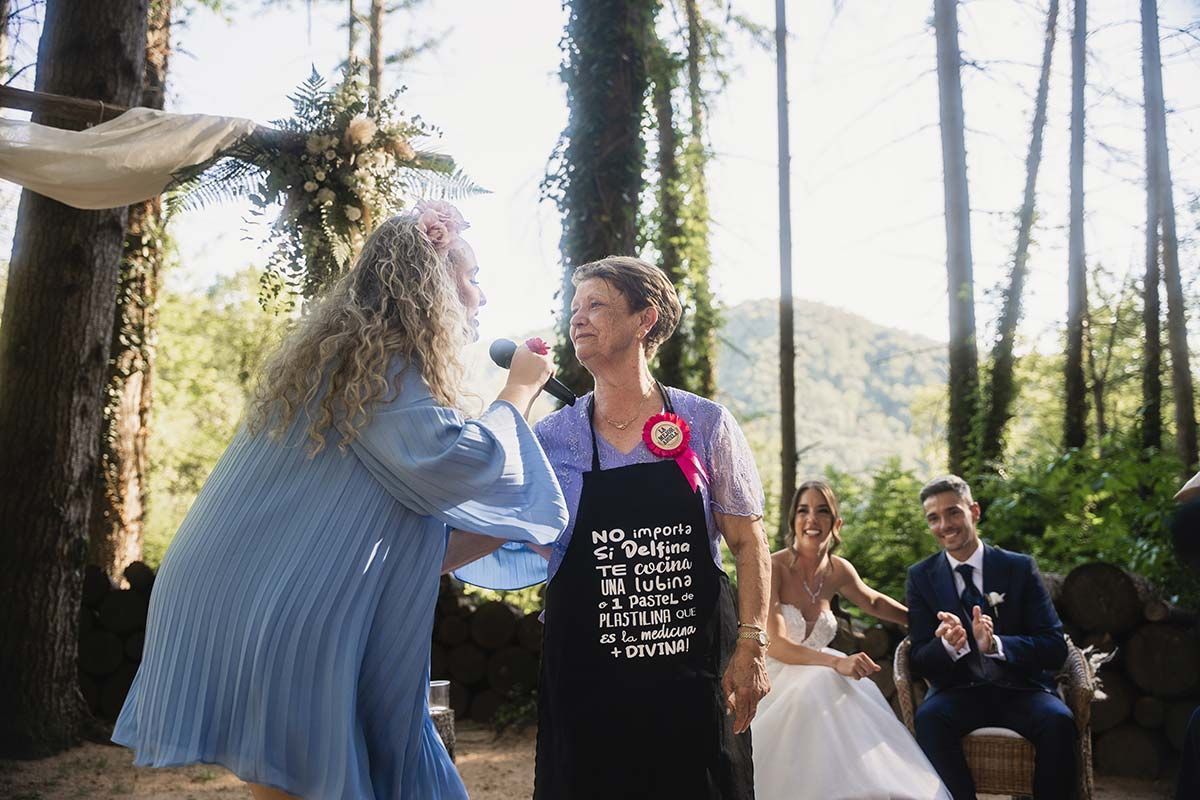 Una mujer con un delantal está cantando en un micrófono frente a unos novios.