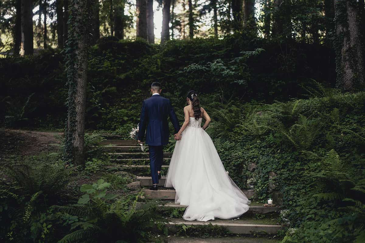 Una novia y un novio bajan las escaleras en el bosque.